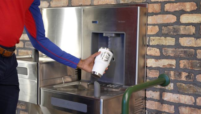 A Cubs filling up on some refreshing water from the DRS120 DropSpot On-wall Bottle Filler with Bi-level Cooler
